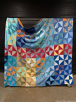 Full view of pinwheel patchwork quilt hung for scale