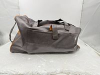 Left side view of dark brown faux leather duffel bag, showing exterior color, material texture and size