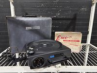 Projector, case, slide binder box and cords on shelf