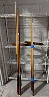 Group of assembled cues leaning against shelving