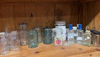 Shelf containing entire assortment of clear and aqua jars and bottles