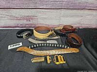 Overview of all belts, buckles and accessories laid out on black surface