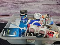 Overall view of clear tote showing packaged bulbs, torchiere rings, appliance bulbs and security light fixture