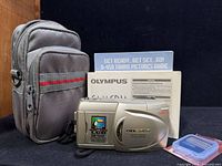 Front view of camera with pouch, manuals, memory card case