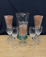 Group shot of four Orrefors wine glasses, two tall footed vases, one hurricane vase with glass filler