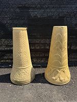 Front view of both cast stone pedestals showing carved designs and color