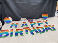 Full layout showing rainbow pop-it letter banner, two heart signs, small topper and string