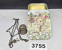 Tin with necklace and lot number visible
