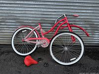 Full view of red step-through cruiser bicycle with detached front section and saddle, pedals nearby