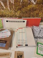 Overview of multiple packaged card-making supplies including David Tutera packs, floral note cards, string-tie envelopes