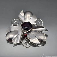 Full view of silver floral brooch with garnet centre