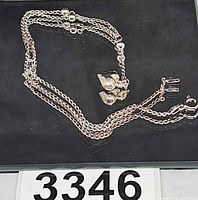 Full view of necklace coiled showing multi strands, heart charm, clasp
