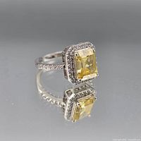 Angled view showing front of ring, yellow center stone, halo and pavé shoulders