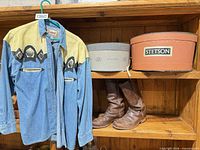 Shirt, two hat boxes and boots displayed on shelf