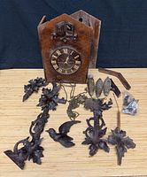 entire lot laid out showing clock case, carved pieces, weights, chains