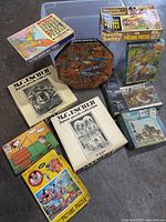 Group shot of all eight puzzle boxes in and around clear bin