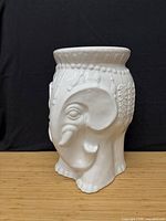 Side profile of white ceramic garden stool showing elephant motif and glazed finish