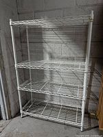 Front view of entire white metal wire shelving unit with four shelves