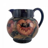 Left-front view of Moorcroft Big Poppy pitcher showing floral decoration and chip on spout edge
