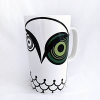Front view showing green-eyed owl graphic and mug form