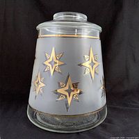 Front view of frosted glass canister showing gold atomic star graphics and lid fitted