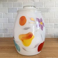 Front view of white milk glass canister showing painted fruit and flower motif
