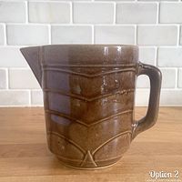 Front view showing spout, chevron ribs, glaze, and chip