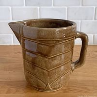 Front view of gloss brown chevron ribbed pitcher showing spout and ribbing
