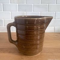 Front view showing caramel brown ribbed pitcher with handle and spout