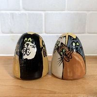 Front view of both cat-themed shakers showing painted faces