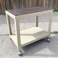 Full view of beige metal cart with brown vinyl top and casters