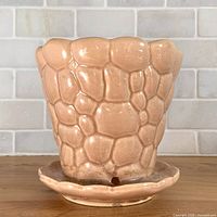 Front view of peach pebble-texture McCoy planter on attached saucer