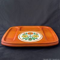 Top view of orange-stained wood board showing three recessed sections and central floral tile