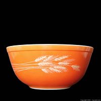 Side view of orange Pyrex Autumn Harvest bowl showing wheat pattern