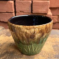 Front view showing brown and green drip glaze and embossed pattern