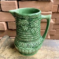 Left-front view showing overall form, spout, handle, and embossed design
