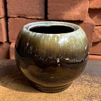 Front view of round olive green drip glaze planter