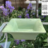 Front angled view showing pale green glaze, flared square form, floral embossing