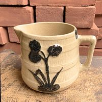 Front view showing navy lily relief, spout and rope handle