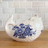 Left profile of fish-shaped creamer showing blue floral transfer pattern and tail handle