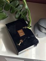Closed black lacquer presentation box with gold plaque and tassel key