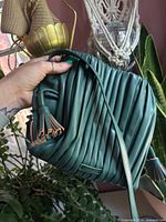 Front view of teal pleated Fossil bag with tassels and strap