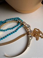 Headband, turquoise bead strand and gold chain laid out together