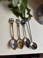 Front view of four souvenir spoons showing bowls and finials