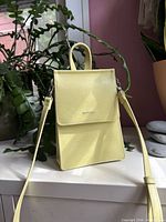 Front view of yellow Matt & Nat mini crossbody bag with flap and strap