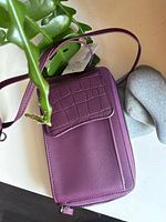 Front view of purple faux leather crossbody wallet with strap and tag attached