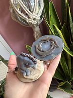 Hand holding resin foal figurine and agate coaster together