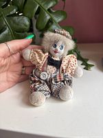 Front view of small clown plush doll showing outfit, face, and size reference with hand