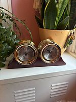 Front view of clock and barometer on wood base