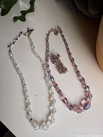 Overview of two necklaces and earrings on surface